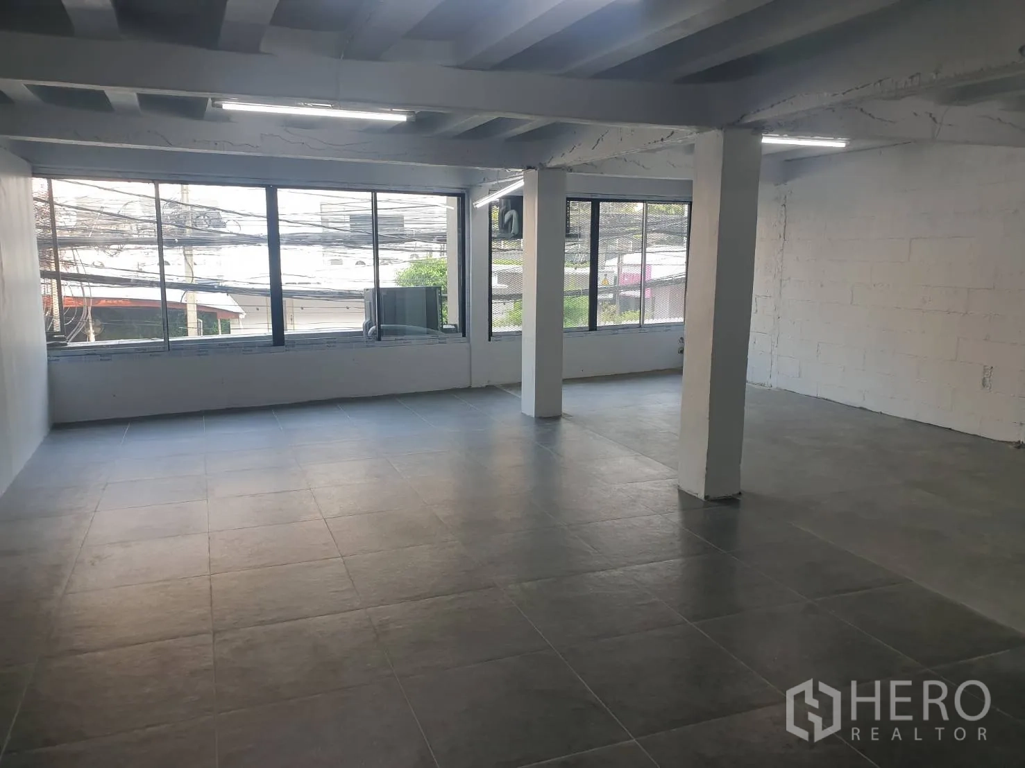 Retail Space for rent in Khlong Toei, Bangkok - Spacious retail floor with large windows, street views, exposed ceiling beams and tiled floor.