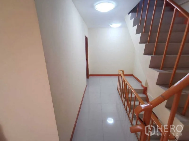 Shophouse for rent in Suan Luang, Bangkok - Well-lit corridor next to staircase with glossy floor tiles.