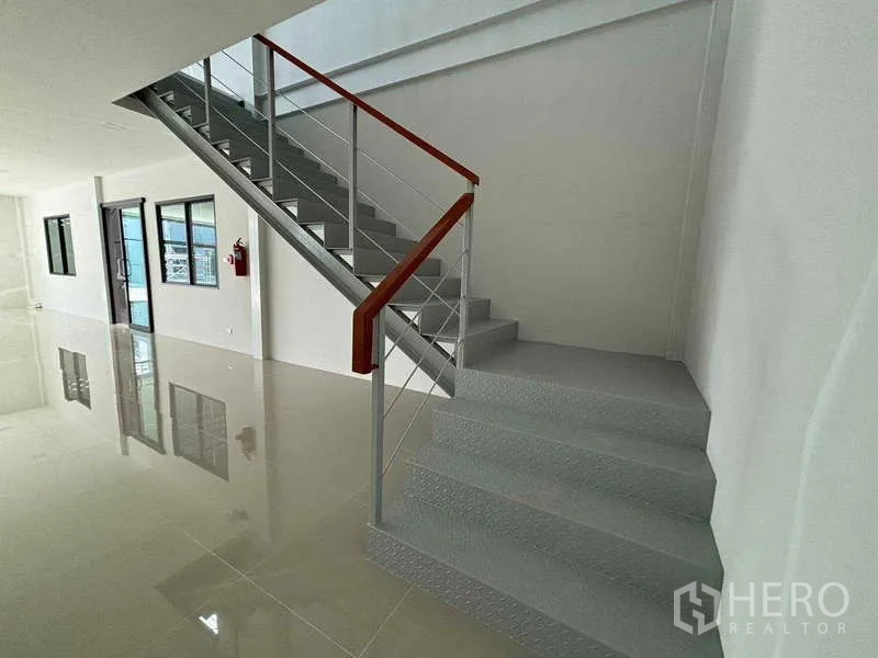 Factory for rent in Bang Bo, Samut Prakan - Bright office lobby with steel staircase, red handrail and glossy tile floor inside a modern factory.