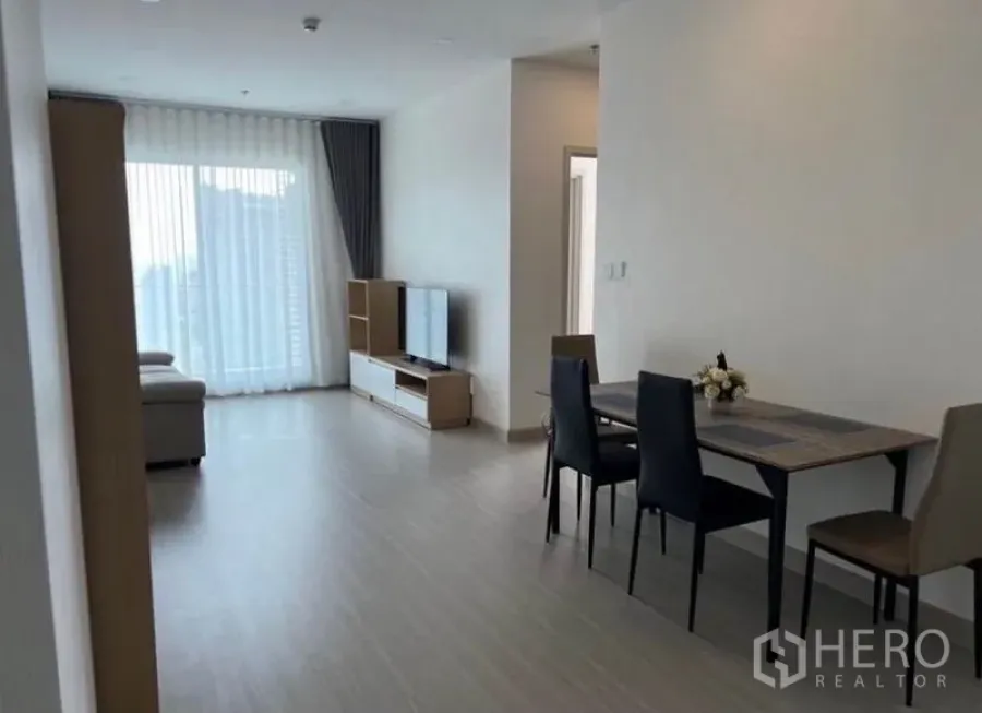 Condominium for rent in Bang Rak, Bangkok - Open-plan living room facing the balcony, TV stand and dining table for four.
