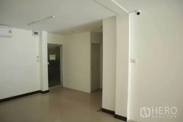 Retail Space for rent in Watthana, Bangkok - Corner of the retail unit showing doorway to the bathroom, wall-mounted AC, and a small utility nook.