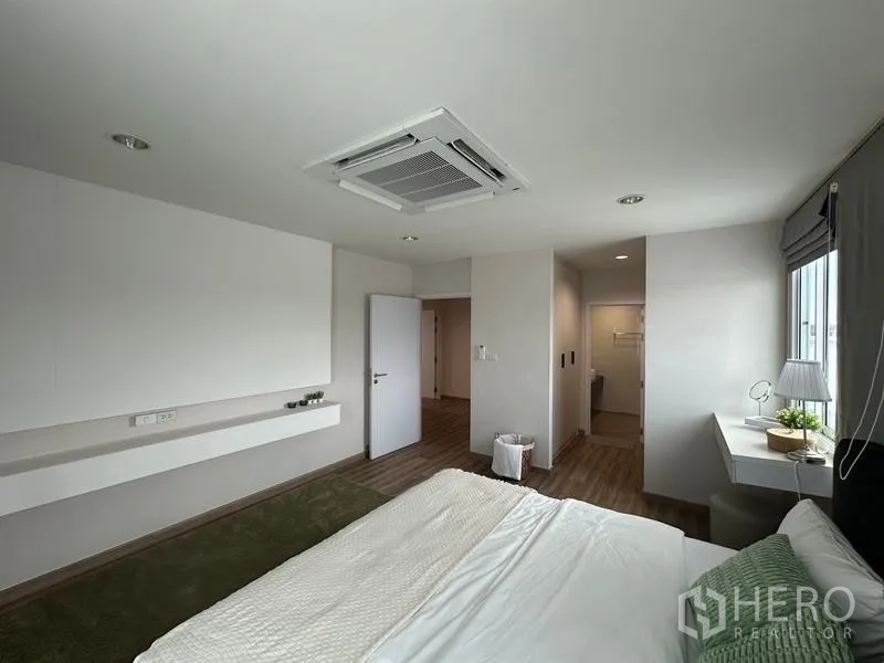 Warehouse for sale in Pathum Thani - Master bedroom angle showing built-in desk, entryway and ensuite zone with ceiling AC.