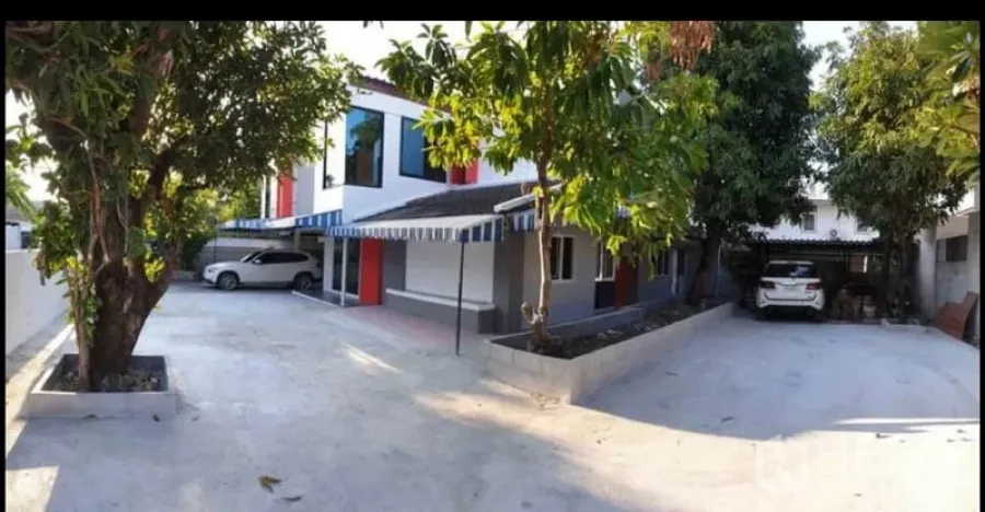 Detached House for rent in Lat Phrao, Bangkok - Front exterior of a two‑storey detached house in Lat Phrao with wide concrete driveway, mature trees and dual carports.