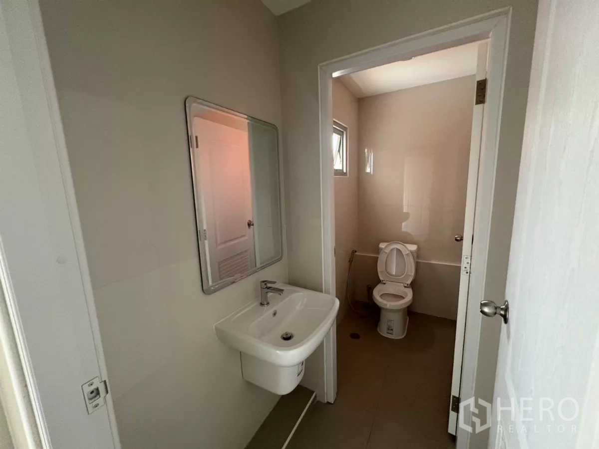 Factory for rent in Bang Phli, Samut Prakan - Washbasin area with mirror and separate toilet cubicle in office bathroom.