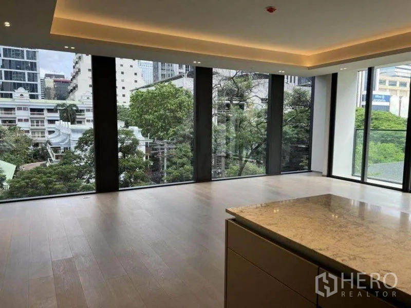 Condominium for rent in Pathum Wan, Bangkok - Corner living space with panoramic windows and garden-city outlook.