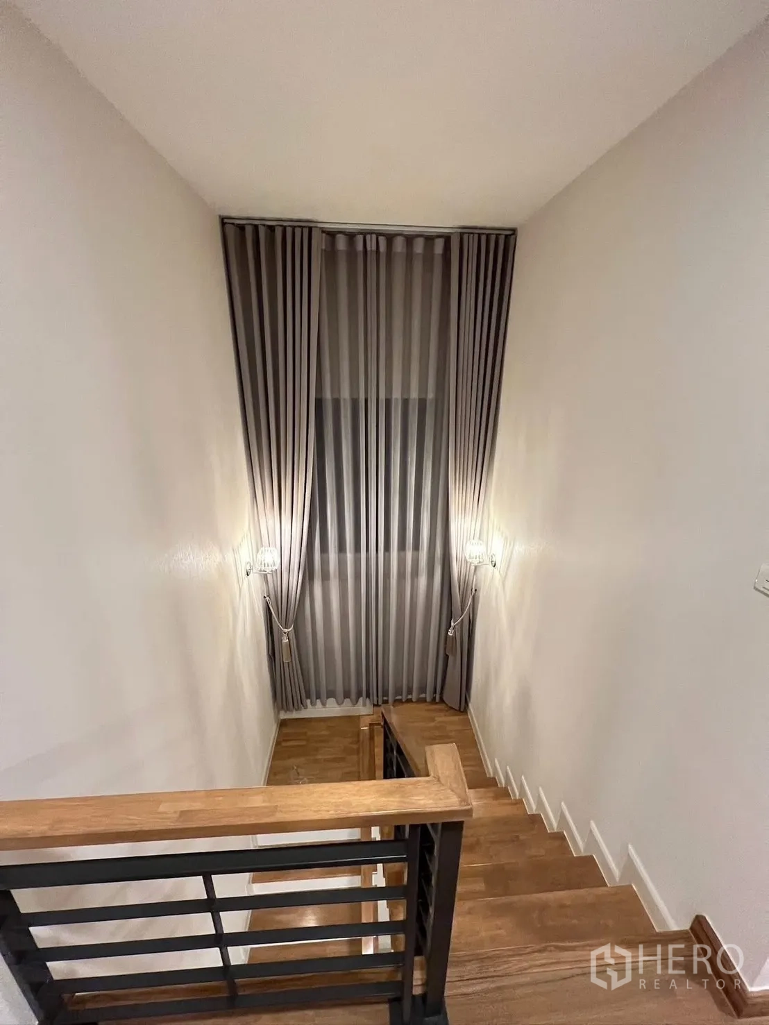 Detached House for rent in Prawet, Bangkok - Staircase with wooden steps, handrail and a tall curtained window.
