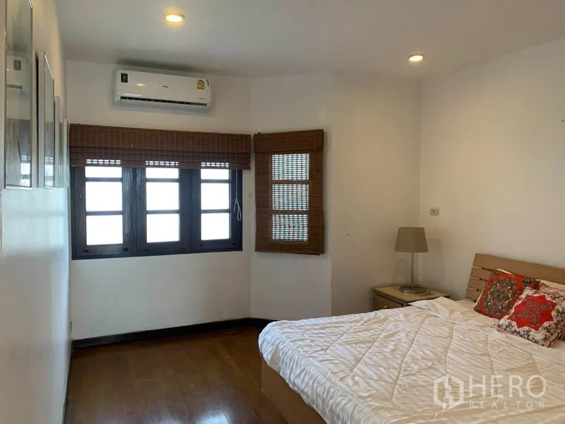 Townhouse for rent or sale in Phra Khanong, Bangkok - Cozy bedroom with a double bed, wooden blinds, recessed lights and air conditioner.