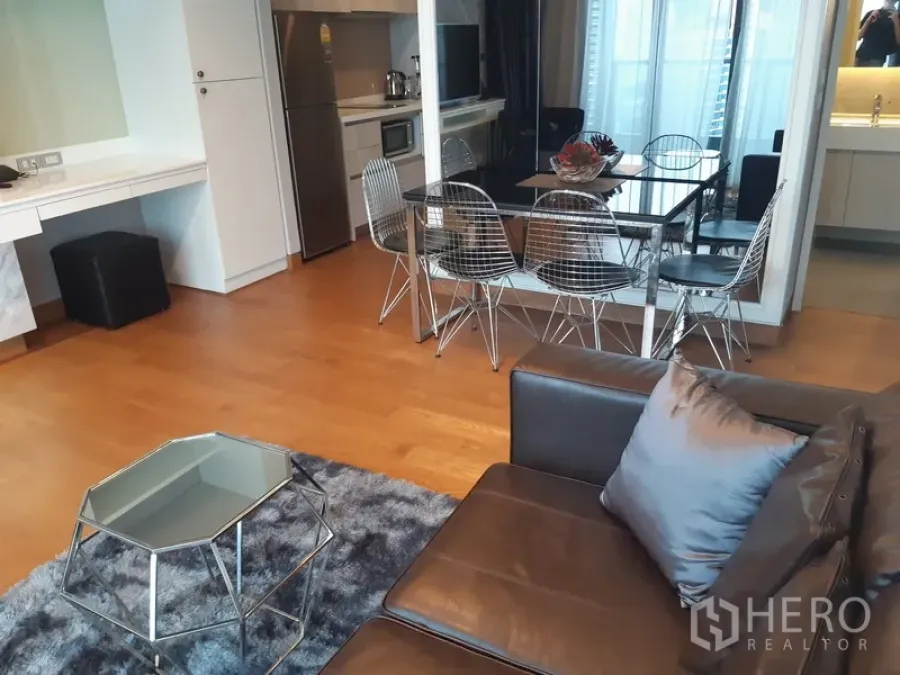 Condominium for rent in Khlong Toei, Bangkok - Dining zone with six metal chairs beside the kitchen and a mirrored wall for spacious feel.