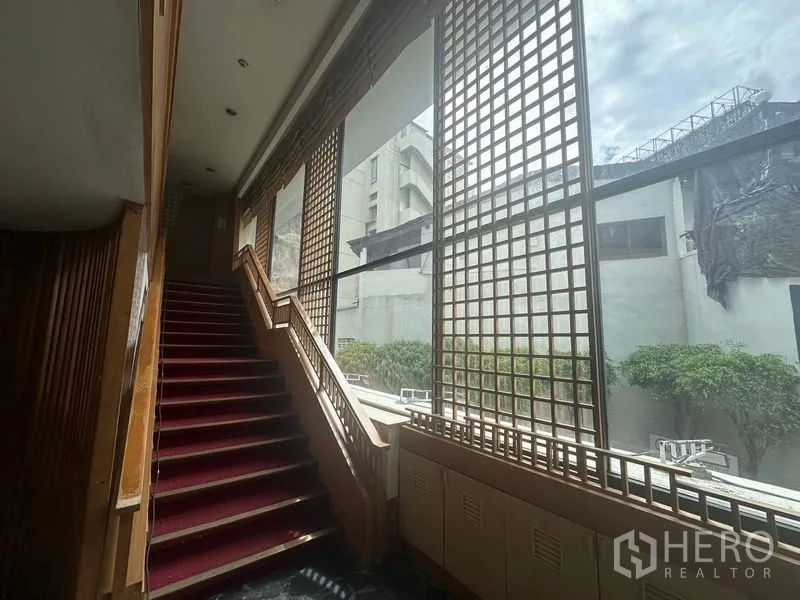 Retail Space for rent in Bang Rak, Bangkok - Staircase with red carpet beside tall lattice windows overlooking the city.