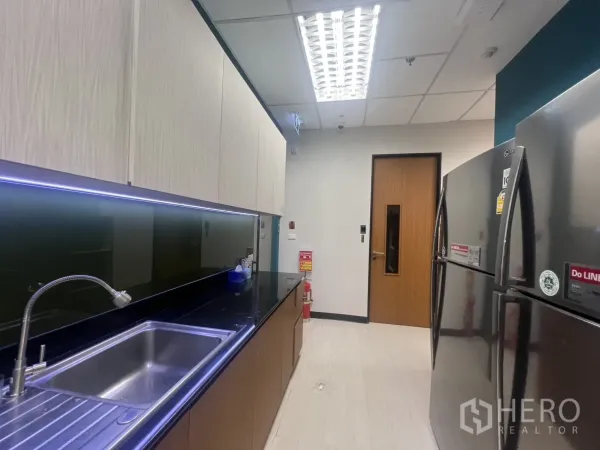 办公空间 出租在Huai Khwang, Bangkok - 茶水间带不锈钢水槽、黑色台面、浅木柜与双门冰箱。
