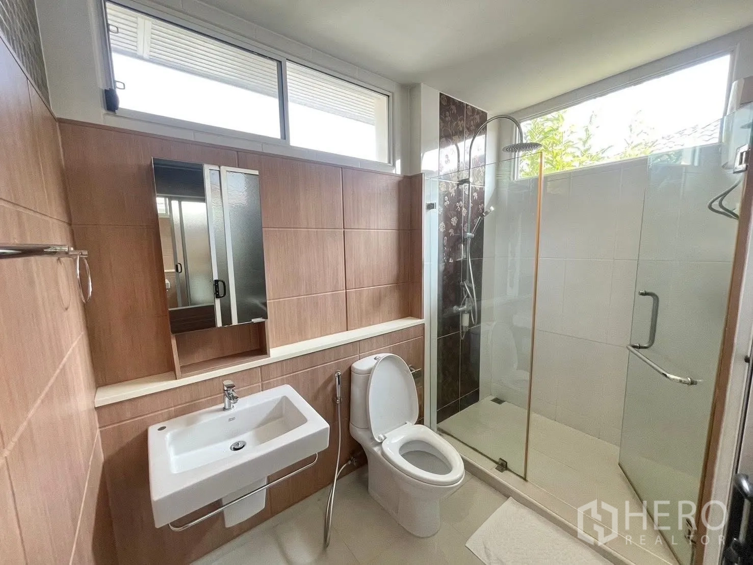 Detached House for rent in Prawet, Bangkok - Bathroom with glass shower, wall tiles, mirror cabinet and basin.