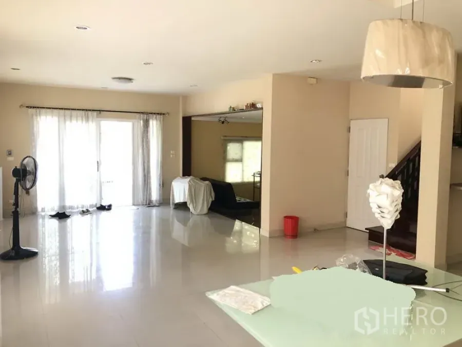 Detached House for rent or sale in Bang Kapi, Bangkok - Bright open-plan living area with glossy tile floors, sheer curtains and a staircase.