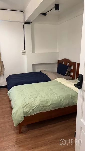 Home Office for rent or sale in Phra Khanong, Bangkok - Compact bedroom with two single beds and wooden flooring.