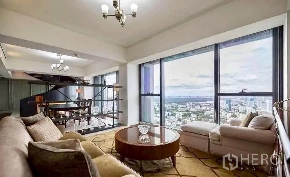 Condominium for rent in Sathon, Bangkok - Seating area with display shelving and wall-to-wall windows overlooking Bangkok’s skyline.