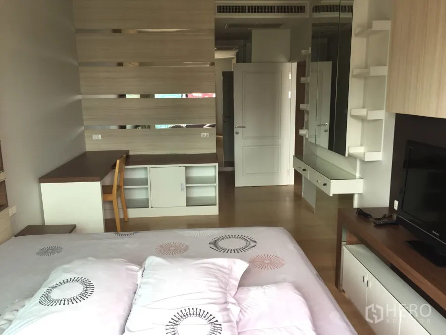 Condominium for rent in Bangkok - Bright bedroom with built-in desk, mirrored shelving and wood floors in Bangkok condo.