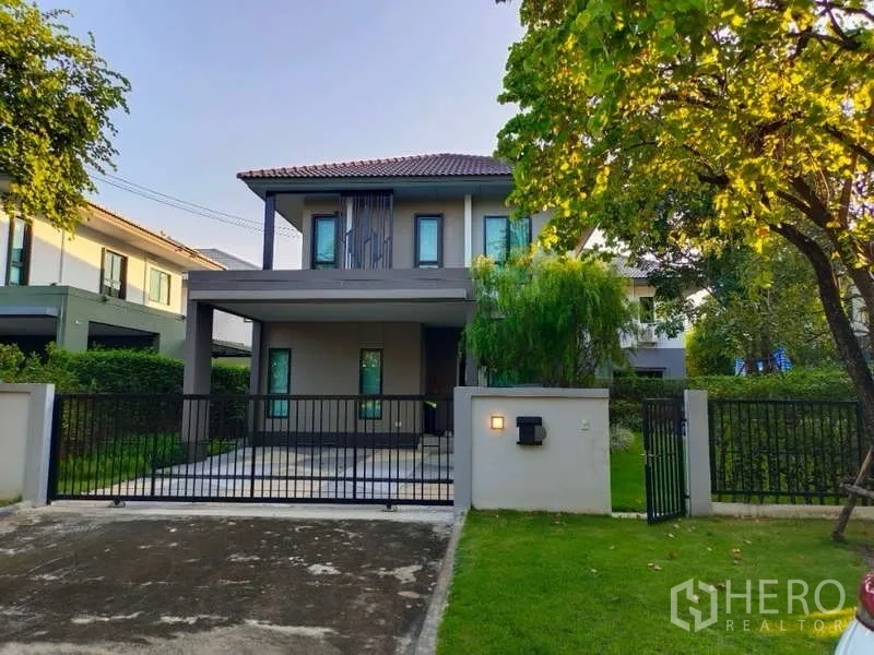 Detached House for rent in Bang Phli, Samut Prakan - Front elevation of the house with covered carport and black metal fence.