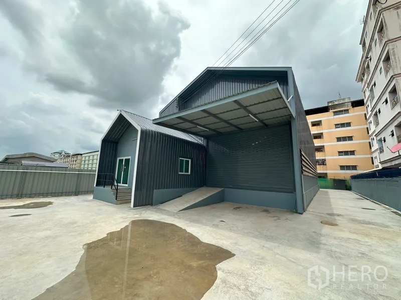 工厂 出租在Khlong Luang, Pathum Thani - 宽阔混凝土院场，设有雨棚装卸平台、卷帘门与办公侧楼。