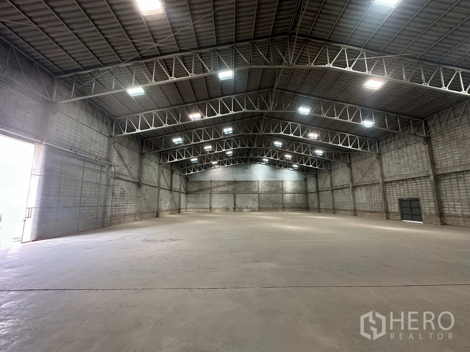 Warehouse for rent in Phra Nakhon Si Ayutthaya - Bright, expansive warehouse interior with metal trusses and double doors.