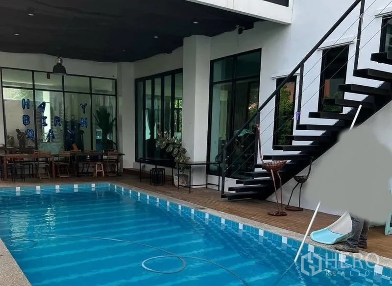 Detached House for sale in Pak Kret, Nonthaburi - Private swimming pool with timber deck, covered terrace and black metal stairs to the upper floor.