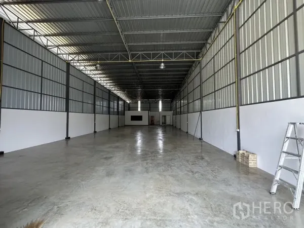 Warehouse for rent in Khlong Sam Wa, Bangkok - Interior of the warehouse with high ceiling, steel trusses, and polished concrete floor.