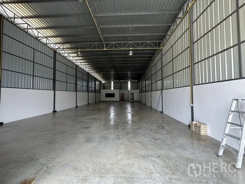 Warehouse for rent in Khlong Sam Wa, Bangkok - Interior of the warehouse with high ceiling, steel trusses, and polished concrete floor.