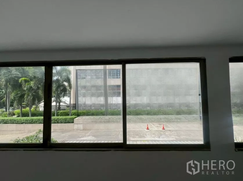 Retail Space for rent in Pathum Wan, Bangkok - Large interior window looking out to landscaped palms and a sidewalk in front of the building.