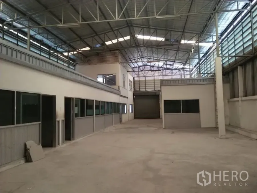 Warehouse for rent in Suan Luang, Bangkok - Spacious warehouse interior with high steel roof, mezzanine office, and roller shutter.