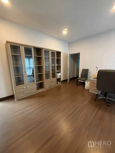 Detached House for rent in Mueang Nonthaburi, Nonthaburi - Study or bedroom with glass-door bookcases, desk area and wood floors.
