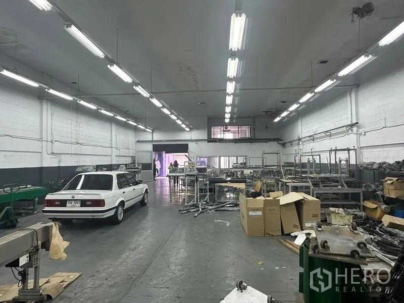 工厂 出租或出售在Khlong Luang, Pathum Thani - 车间内部，可见设备流水线、储物架和夹层办公室窗户。