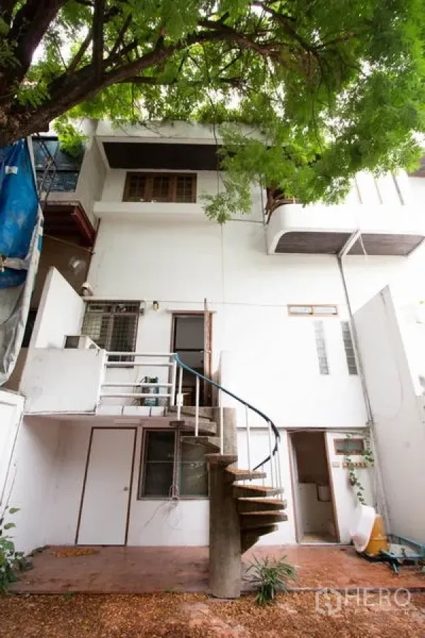 联排别墅 出租在Khlong Toei, Bangkok - 白色联排别墅后立面，螺旋楼梯与大树遮荫。