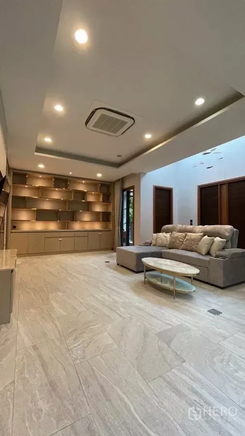 Detached House for rent in Prawet, Bangkok - Bright living room with illuminated built-in shelving, recessed lights and a sofa.