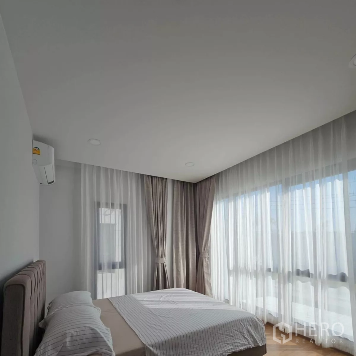 Detached House for rent in Bang Phli, Samut Prakan - Corner bedroom with large windows, sheer curtains and split air conditioner.