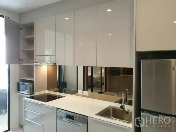 Condominium for rent in Pathum Wan, Bangkok - Contemporary kitchen with stone countertops, built-in cooktop, dishwasher and full-height cabinets.