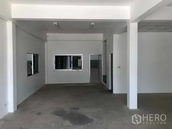 工厂 出租在Khlong Luang, Pathum Thani - 一层前台/办公室，白色墙面、窗户与水泥地面。