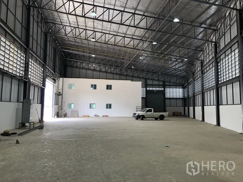 Factory for rent in Samut Prakan - Spacious warehouse hall with two-storey office block and large rear shutter.