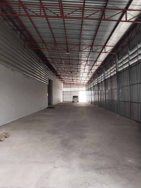 Warehouse for rent in Lat Krabang, Bangkok - Wide drive-through aisle with metal cladding and roof trusses leading to loading gates.