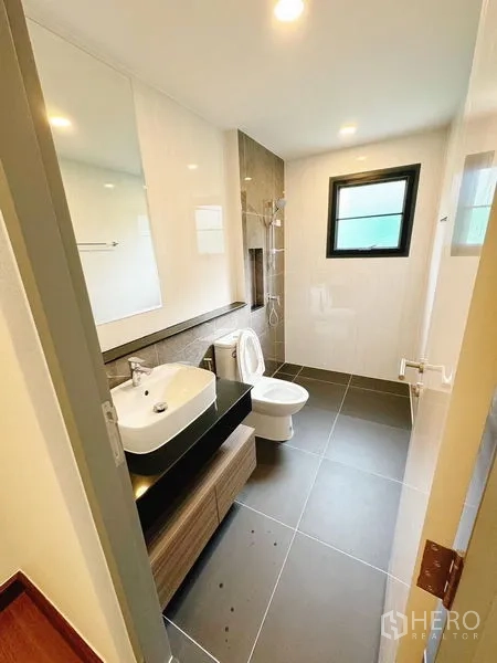 Detached House for rent in Bang Phli, Samut Prakan - Clean bathroom with vanity, toilet and walk-in shower next to a window.