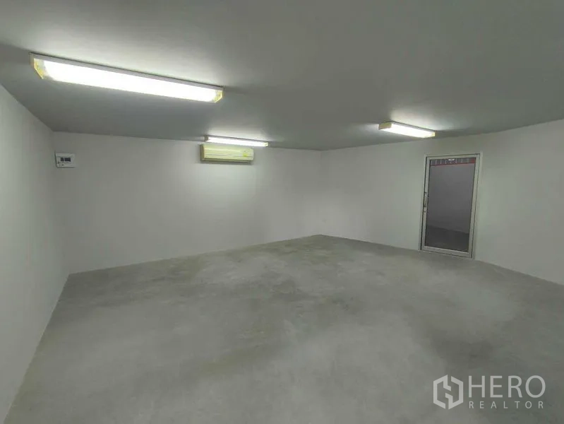 Warehouse for rent in Pak Kret, Nonthaburi - Air-conditioned office room with bright fluorescent lighting and a door to the warehouse.