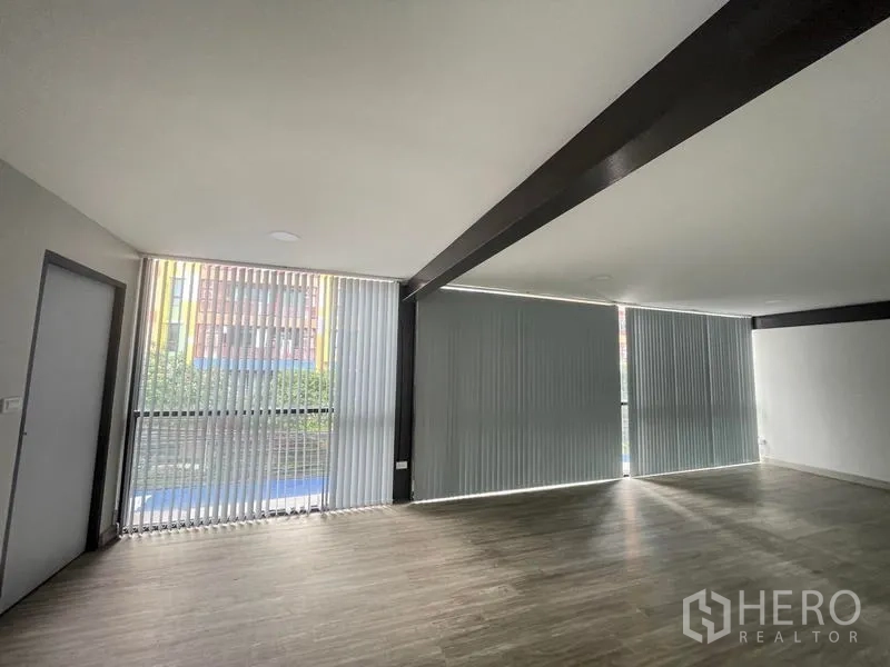 Office Space for rent in Bang Na, Bangkok - Bright corner workspace with floor-to-ceiling windows, vertical blinds and exposed beam ceiling.