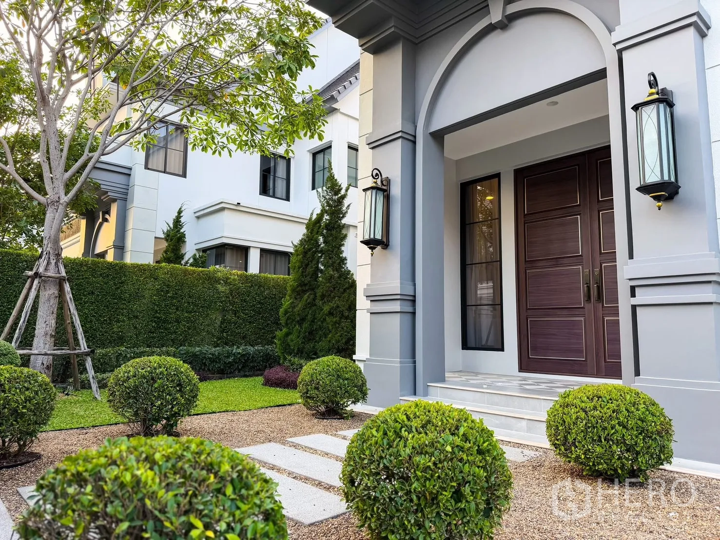 Detached House for rent in Bang Khen, Bangkok - Landscaped front garden with trimmed shrubs, arched porch and lantern wall lights.