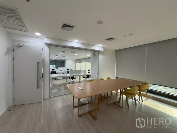 Office Space for rent in Din Daeng, Bangkok - Meeting room with wooden table and yellow chairs beside a glass partition overlooking an open‑plan office.