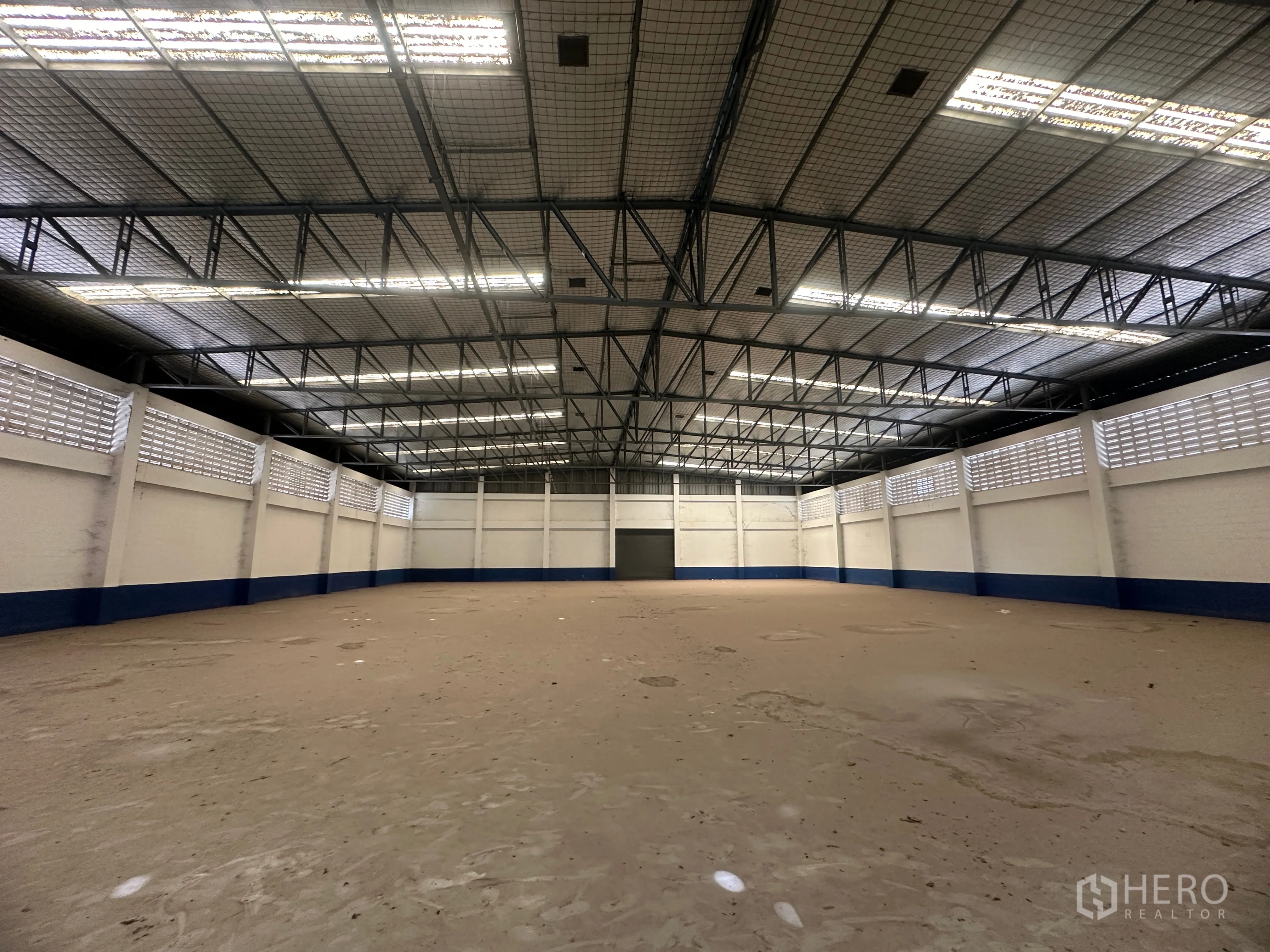 Factory for rent in Bang Pa-in, Phra Nakhon Si Ayutthaya - Wide factory interior facing a large shutter door, bright lighting, and high ceiling.