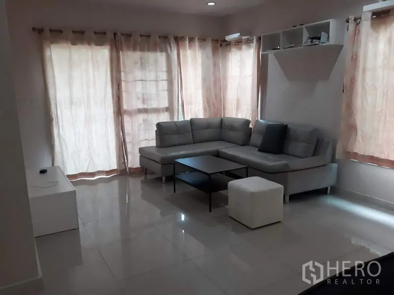 Detached House for rent in Suan Luang, Bangkok - Bright living room with L-shaped grey sofa, coffee table and glossy tiled flooring