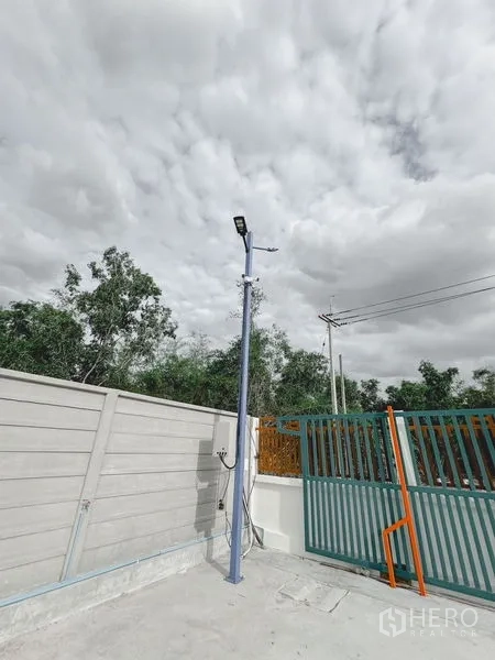 Warehouse for rent or sale in Khlong Luang, Pathum Thani - Close-up of the entrance with a metal sliding gate, pole-mounted lighting and electrical supply.