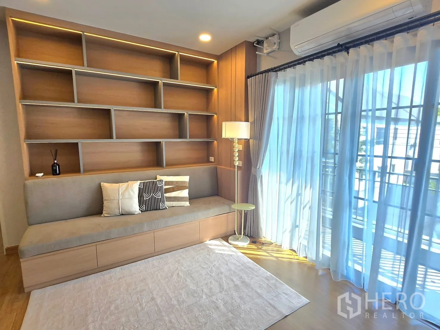 Detached House for rent in Bang Phli, Samut Prakan - Upstairs family room with bench seating, full-height shelving, and sliding doors to a balcony.