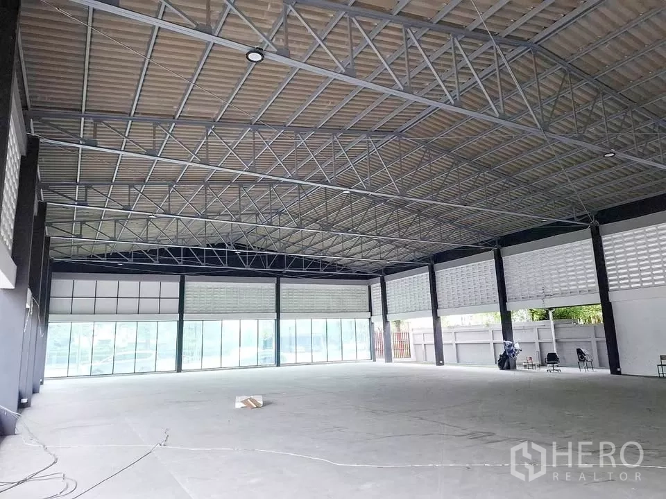 Warehouse for rent in Bang Kapi, Bangkok - Wide-span roof structure with full-height glass frontage creating a bright, flexible showroom space.