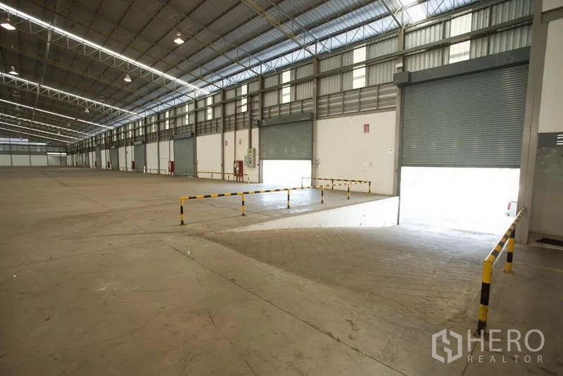 货栈 出租在Si Racha, Chon Buri - 仓库内设装卸坡道与多扇卷帘门，可驱车进出