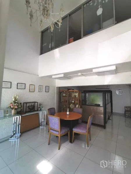 办公空间 出租在Huai Khwang, Bangkok - 挑高大堂，夹层玻璃、吊灯与圆形会客桌。