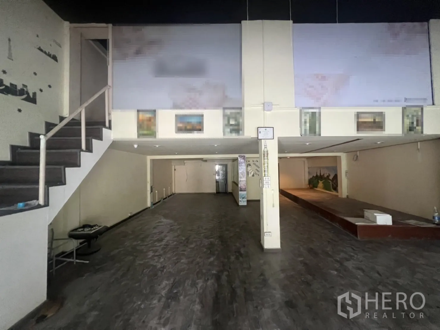 Shophouse for rent in Watthana, Bangkok - Long open-plan interior showing a mezzanine level, staircase and display platform.