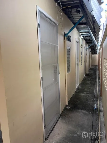 工厂 出租在Lat Lum Kaeo, Pathum Thani - 工厂外侧走廊，沿墙多扇门并有金属雨棚。